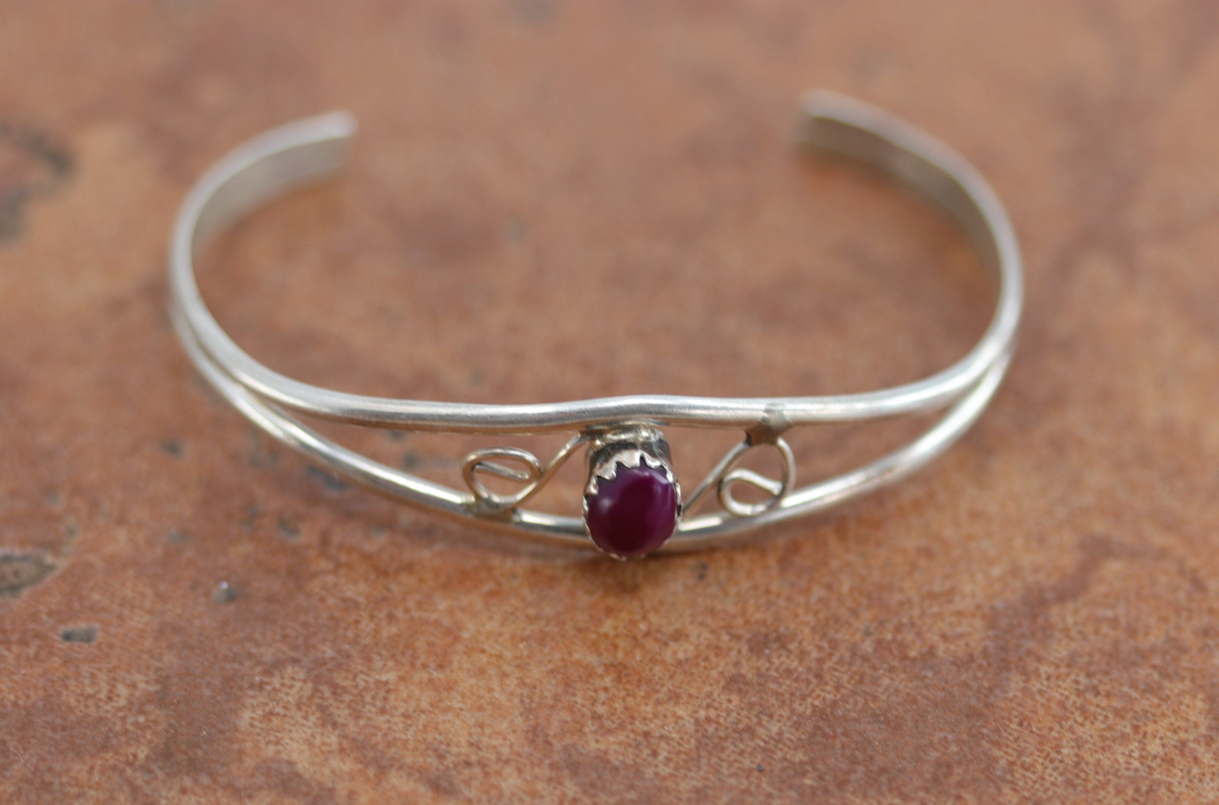 Navajo Native American childrens bracelet. It is made from sterling silver and sugilite. It is about 3 3/8" around and about 3/8" wide at the widest point. The opening is about 3/4", and partly flexible.