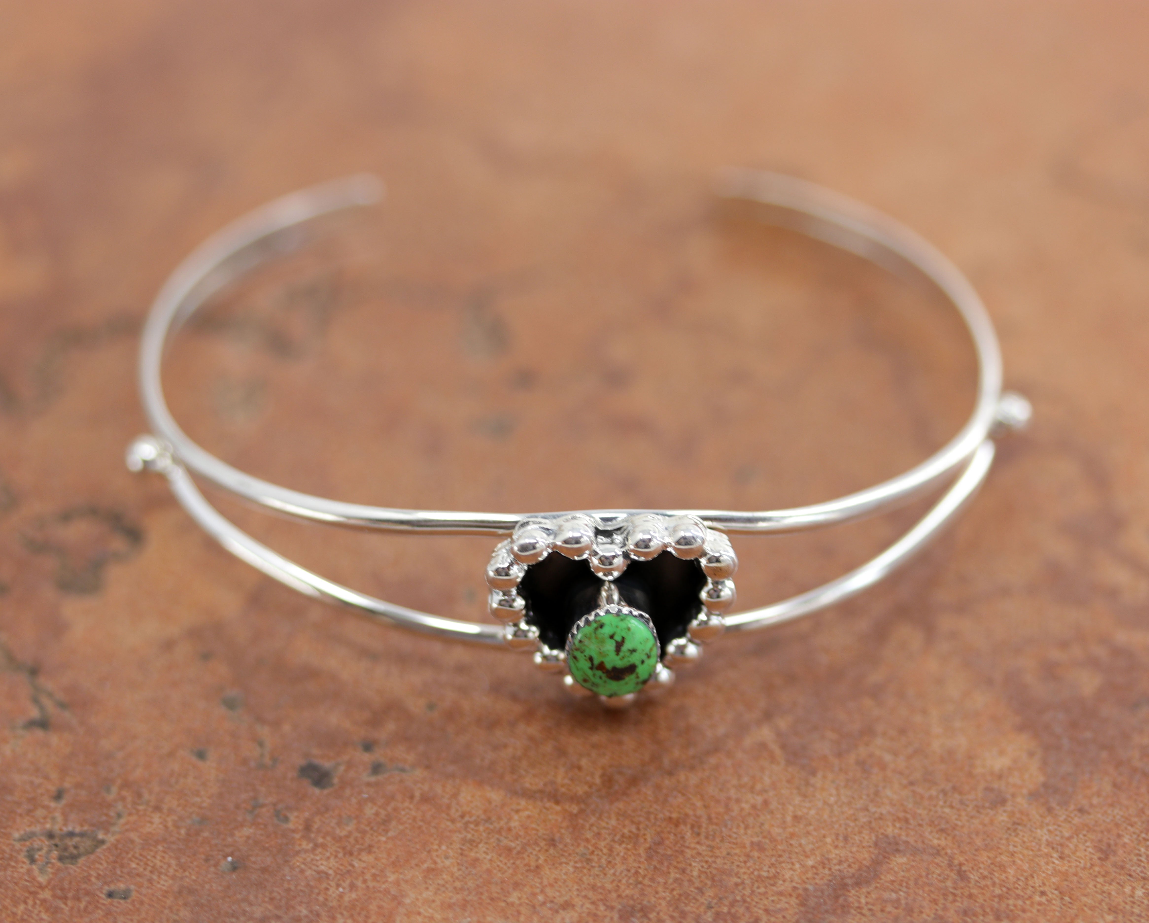 A beautiful Navajo Native American bracelet by Marie Bahe. It is made from sterling silver and green turquoise. It is about 5 3/4" around and 3/4" wide. The opening is about 1 1/4", and partly flexible.