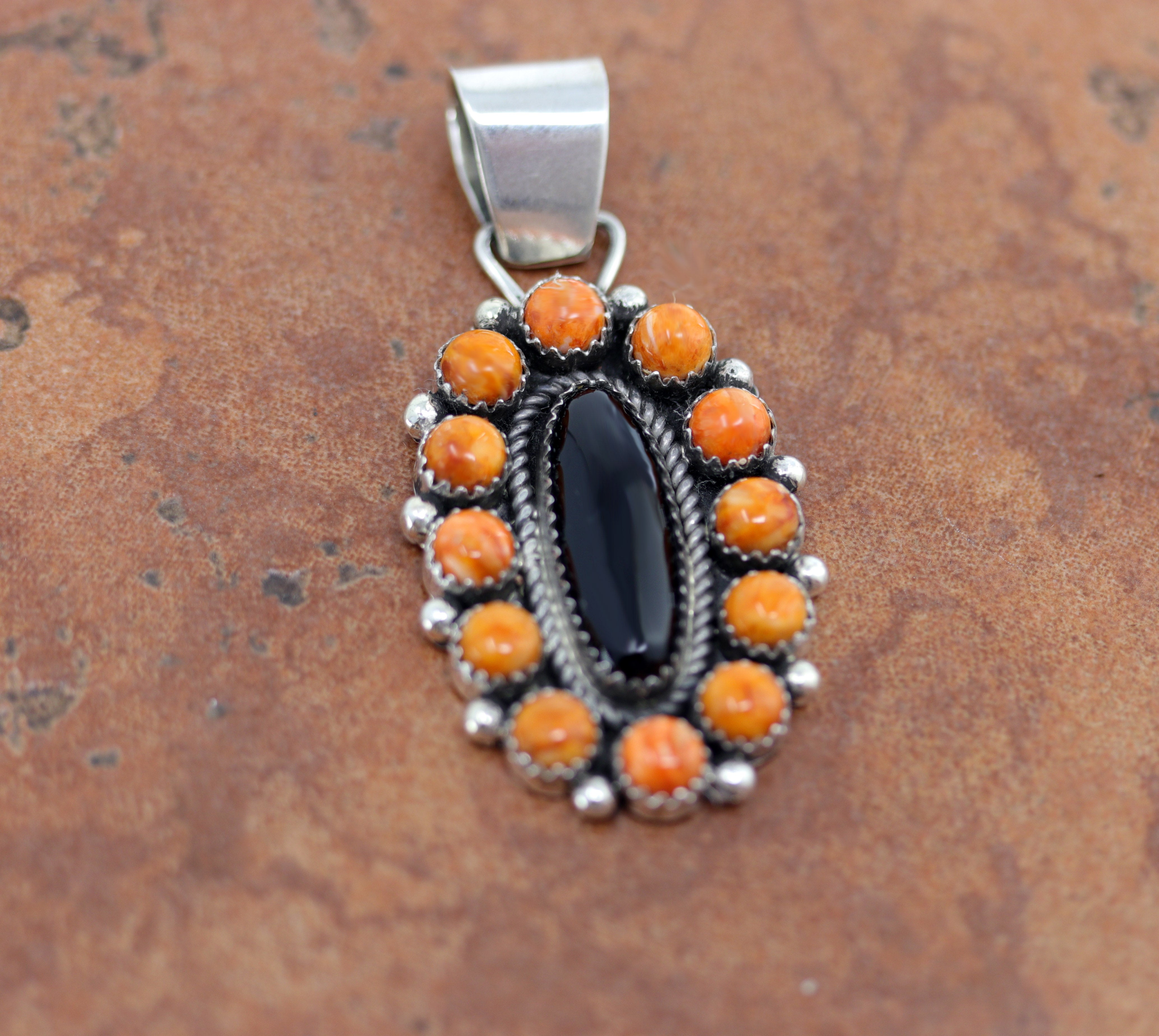 A Beautiful Navajo Native American Pendant. It is made from sterling silver and spiny oyster. The pendant is about 2 1/4" in length and 1" in width.